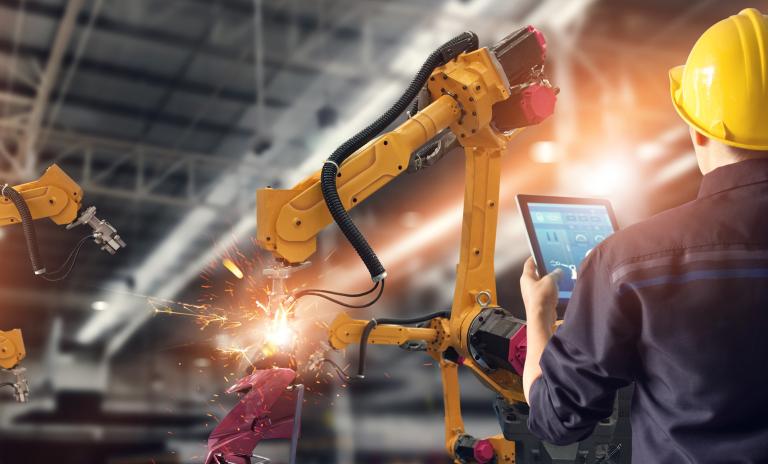 Engineer using tablet check and control automation robot arms machine in intelligent factory industrial on monitoring system software.