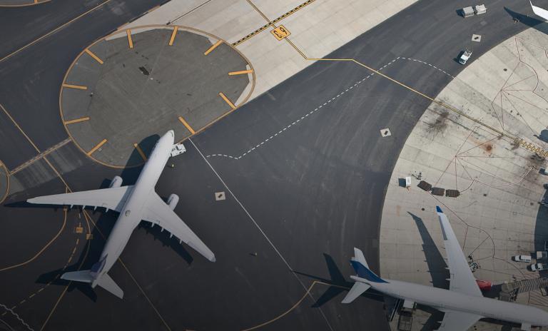 Aerial view of two large commercial airplanes parked on the airport tarmac.