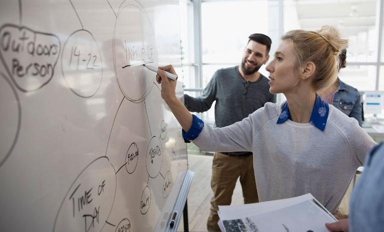 woman writing on whiteboard at work