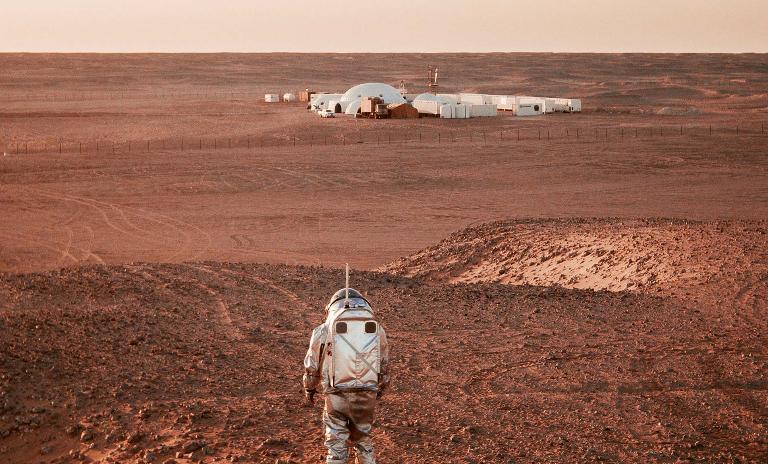 An analog astronaut stands in the Oman desert overlooking base camp, Kepler Station