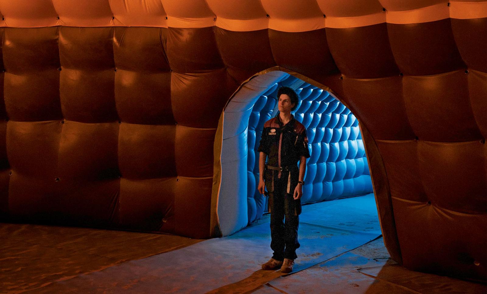 An analog astronaut stands inside base camp in normal work clothes