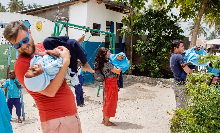 Voluntourists play with children at an orphanage in Zanzibar