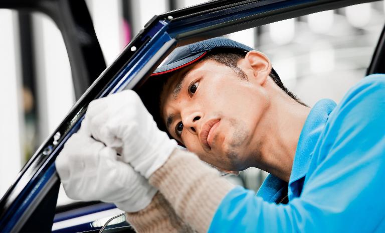 Handcrafted: A Toyota employee assembles a door window frame on the Mirai vehicle without robotic assistance.