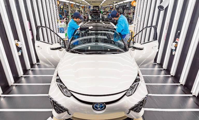 Two workers at Toyota’s Motomachi Plant inspect a Mirai model car