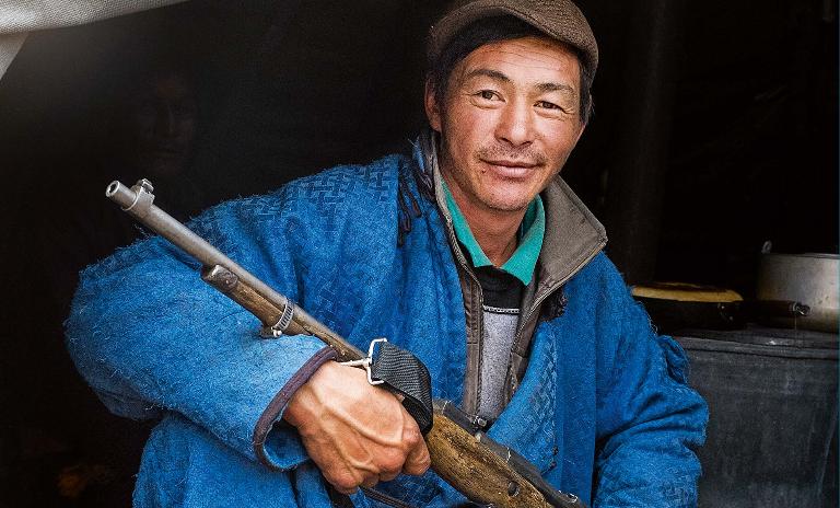 A male member of the Mongolian Tsaatan reindeer shepherd tribe sits with his hunting gun