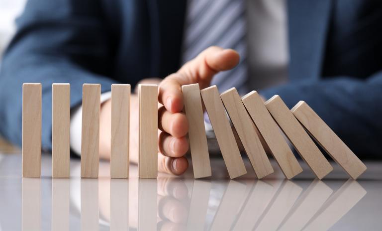 human hand stops falling dominoes