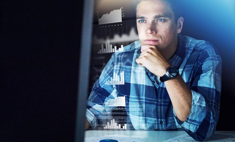man in a plaid shirt in front of a monitor