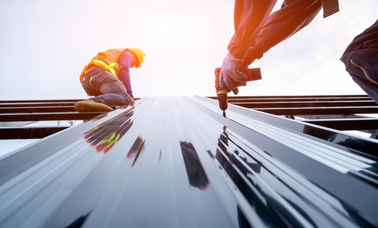 Construction workers using a power tool on a facade