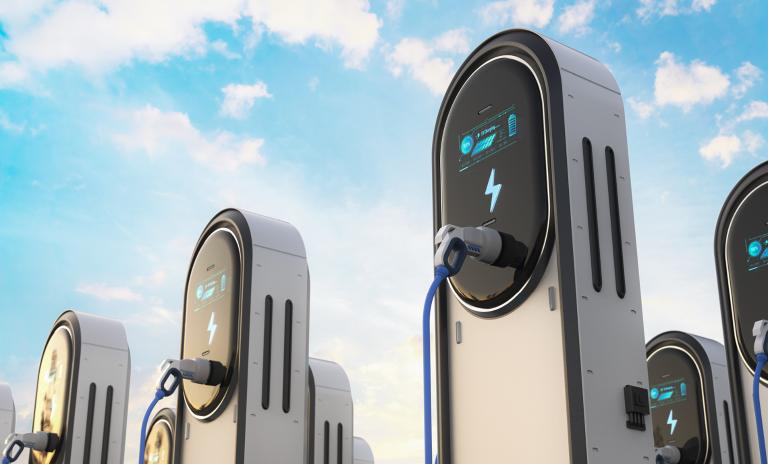 Image of an electric car charging station against a blue sky with clouds.