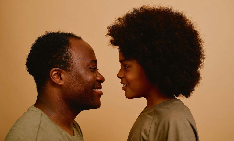A photo of a child and a man looking each other in the eyes and smiling at each other. (c) Robert Rieger