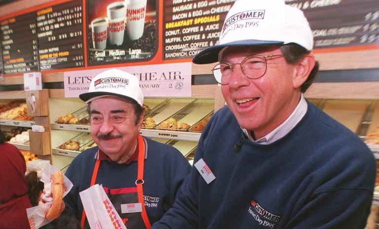 HIER BEDIENT DER CHEF PERSÖNLICH: Auf einem Foto von 1995 gießt der damalige Dunkin’-CEO Robert Rosenberg in dem Original Dunkin’-Donuts-Laden, in dem er 1959 arbeitet, einem Kunden Kaffee ein. Neben ihm steht Michael Vale, der im amerikanischen Fernsehen als „Fred the Baker“ Werbung für Dunkin’ Donuts machte.