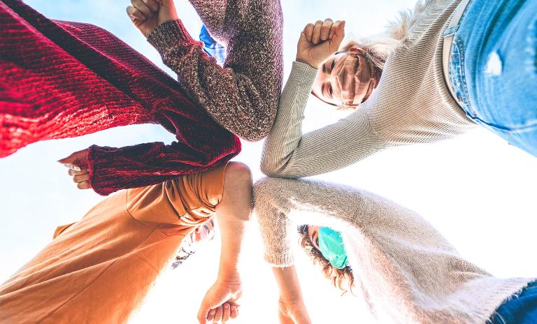 young people with raised elbows in a circle.