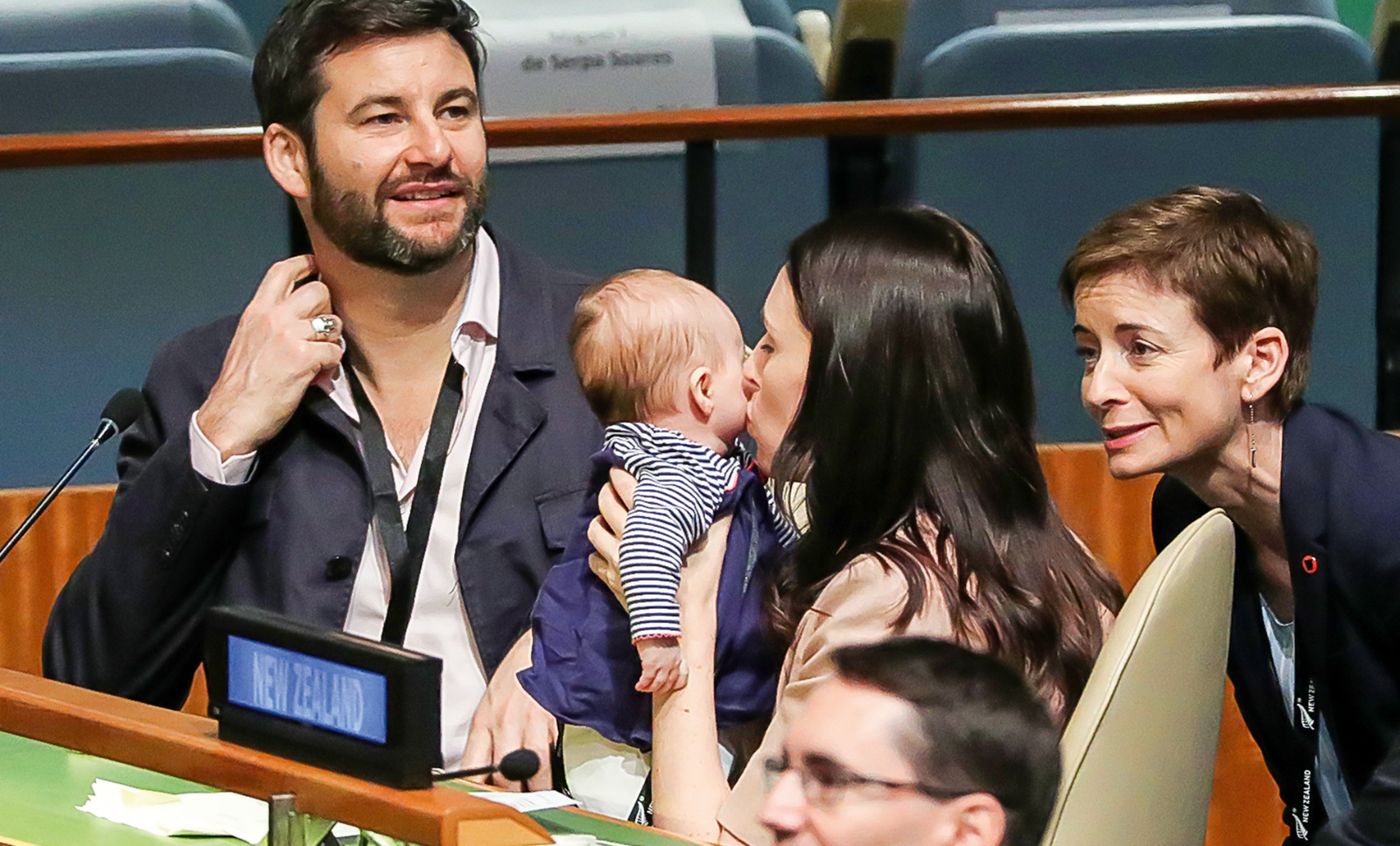 A photo of New Zealand Prime Minister Jacinda Ardern kissing her baby after the 2018 Nelson Mandela Peace Summit at the UN. Her partner sits next to them. (c) REUTERS/Carlo Allegri