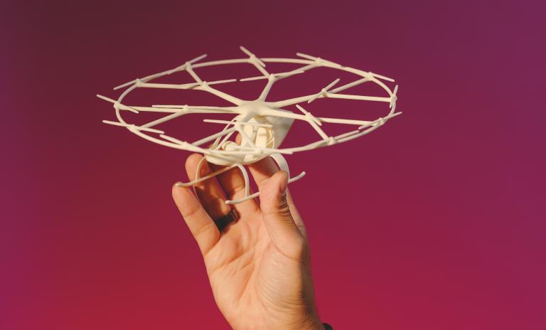 Dirk Hokes Handgelenk, seine Hand und ein Teil des schwarzen Ärmels sind zu sehen, die Hand hält ein cremefarbenes Volocopter-Modell in die Höhe.