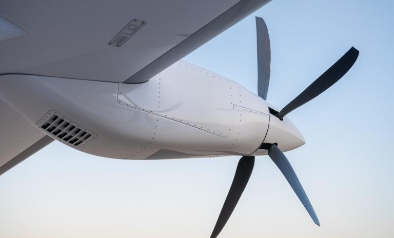 Close-up of an airplane propeller mid-flight against a white-blue sky.