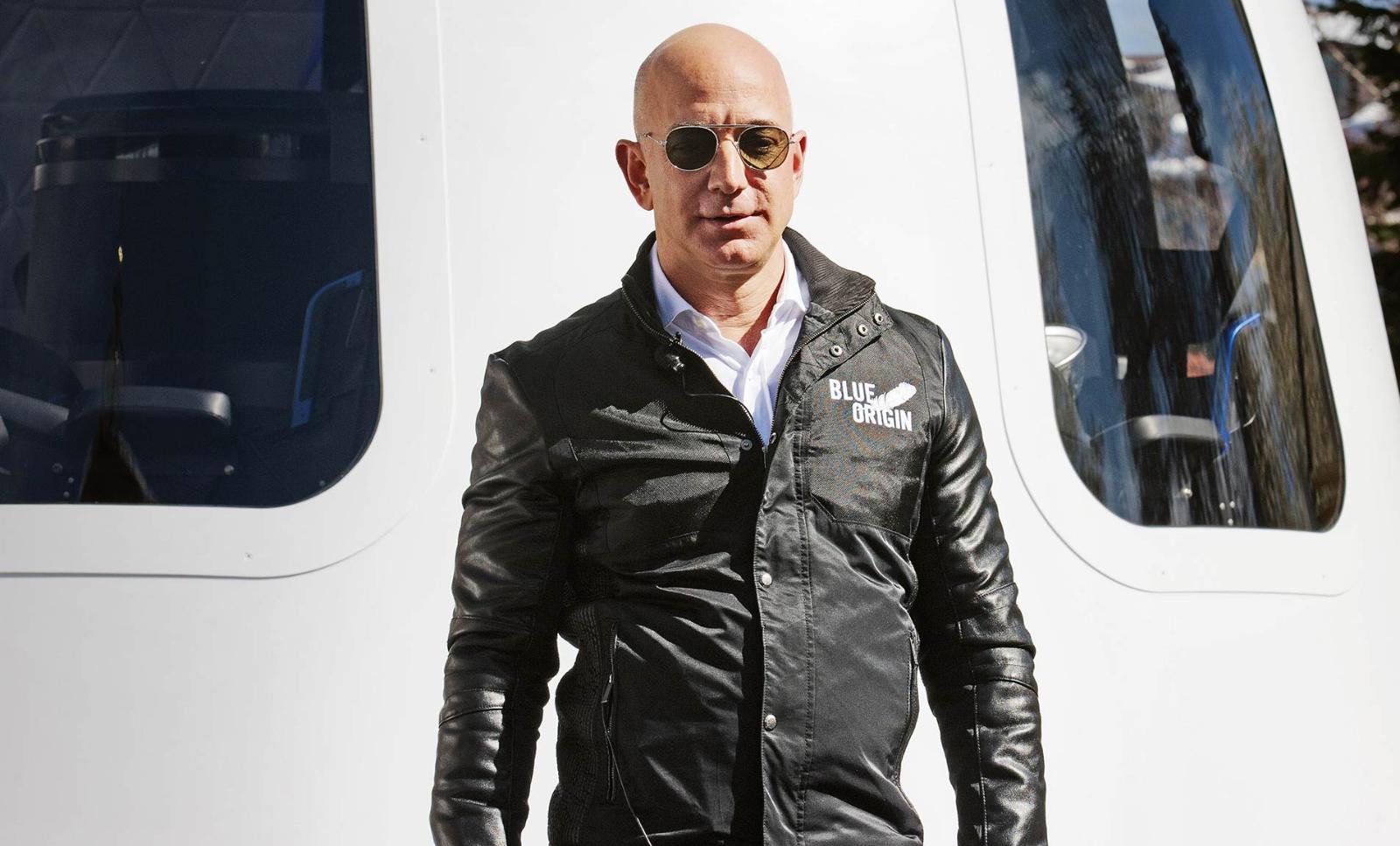 Unveiling the future: Jeff Bezos poses in front of the Blue Origin New Shepard reusable launch system.