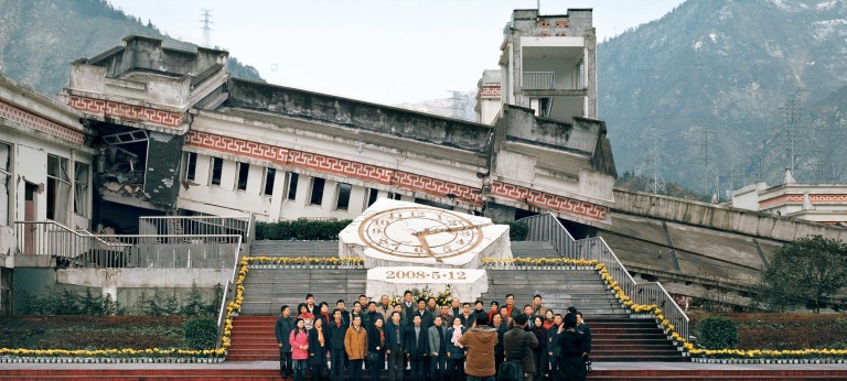 Tourists pose for a photo in front of the remains of a building destroyed in the 2008 Earthquake in China’s Wenchuan Special Tourism Zone