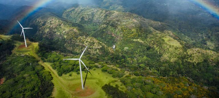Rainbow over windmills in mountainous terrain