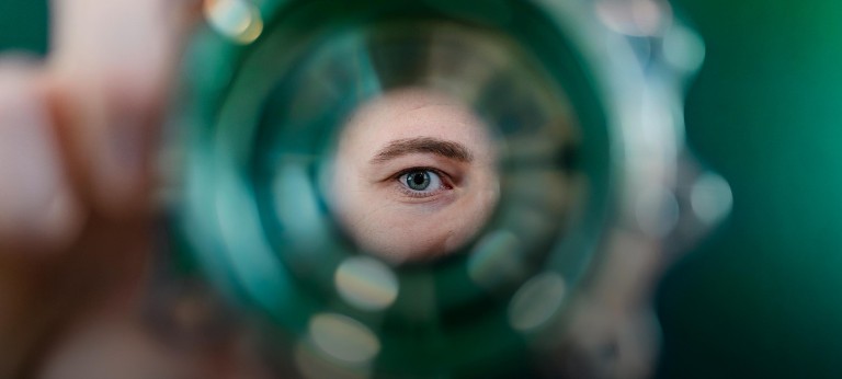 Green human eye looking through a hole